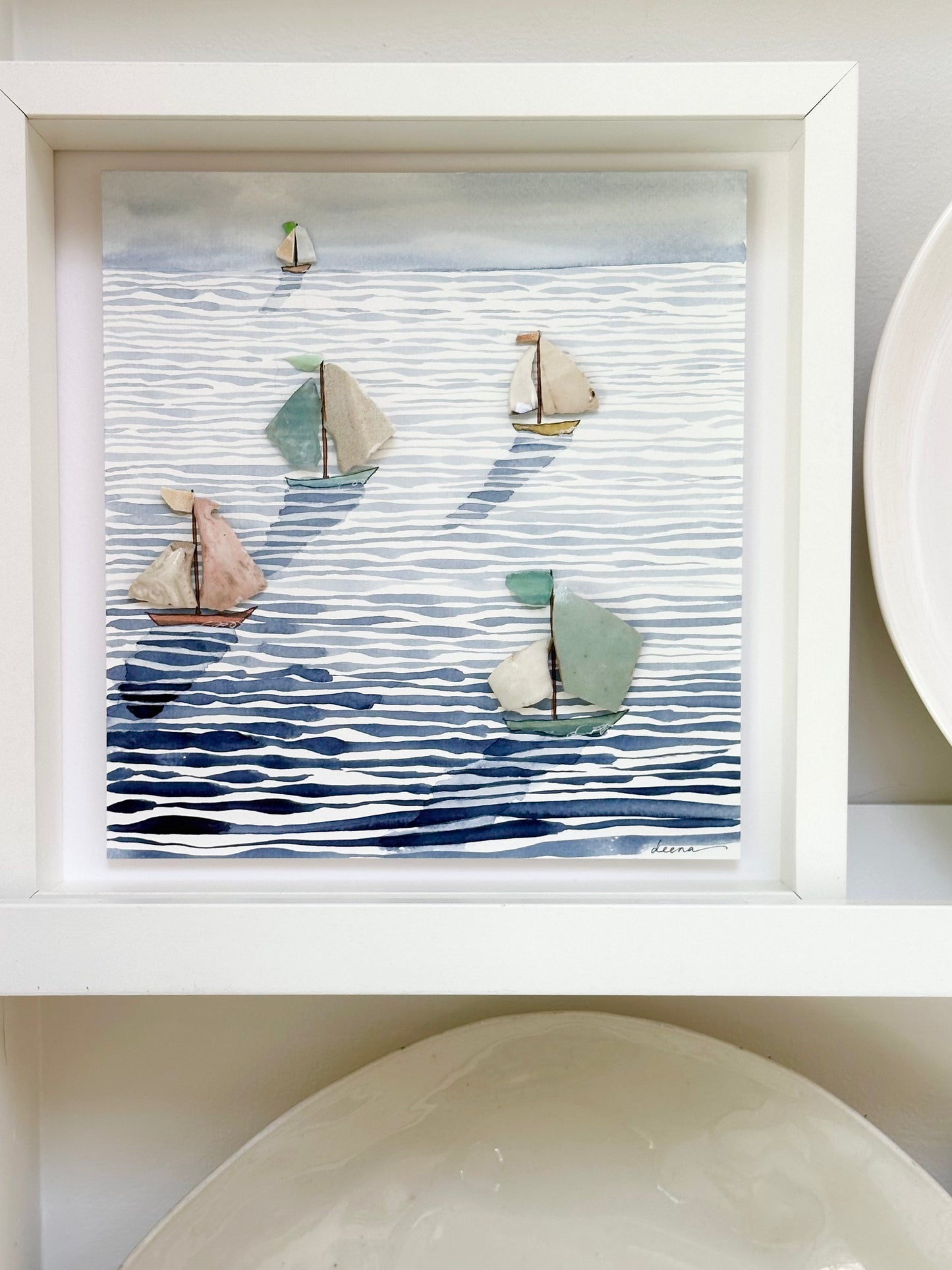 “Mixed media coastal artwork with watercolour waves and sailboats made from reclaimed china shards in a white frame.”