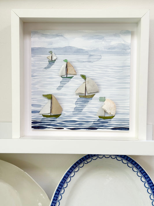 “Mixed media coastal artwork with watercolour waves and sailboats made from reclaimed china shards in a white frame.”