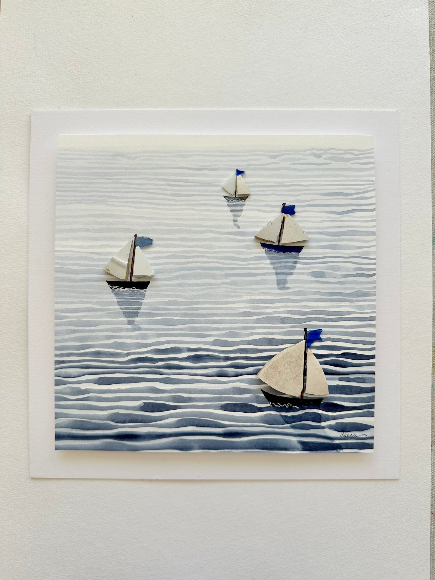 “Mixed media coastal artwork with watercolour waves and sailboats made from reclaimed china shards in a white frame.”