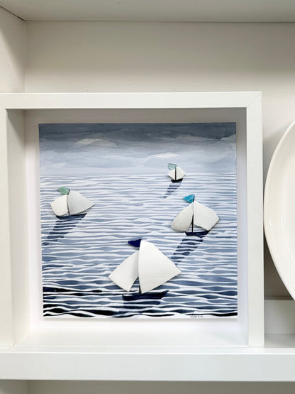 “Mixed media coastal artwork with watercolour waves and sailboats made from reclaimed china shards in a white frame.”