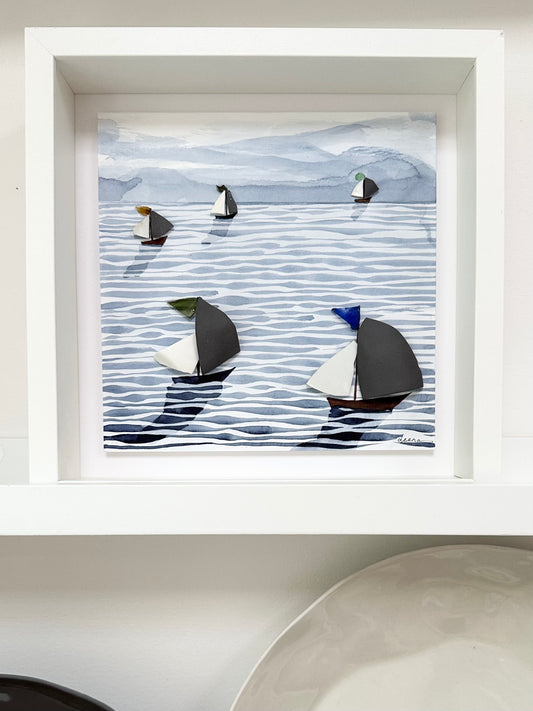 “Mixed media coastal artwork with watercolour waves and sailboats made from reclaimed china shards in a white frame.”