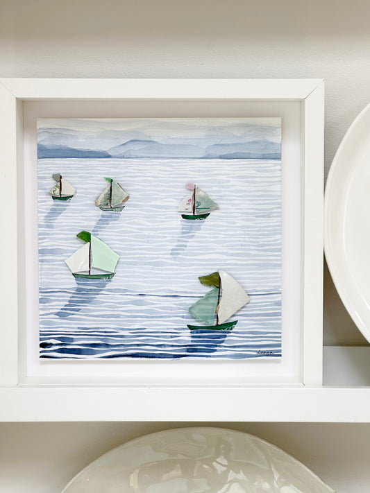 “Mixed media coastal artwork with watercolour waves and sailboats made from reclaimed china shards in a white frame.”