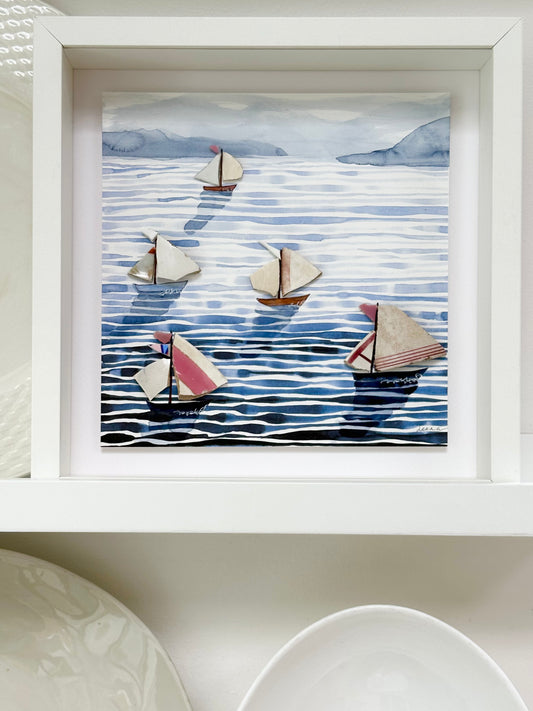 “Mixed media coastal artwork with watercolour waves and sailboats made from reclaimed china shards in a white frame.”