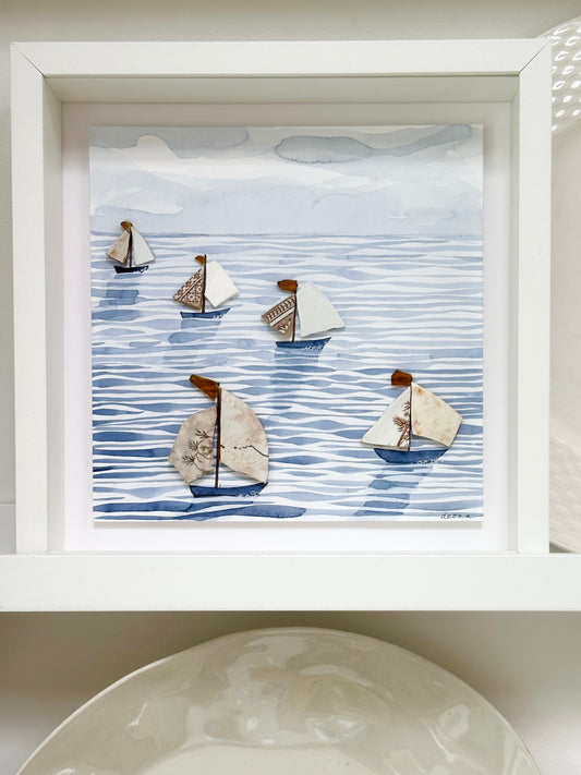 “Mixed media coastal artwork with watercolour waves and sailboats made from reclaimed china shards in a white frame.”
