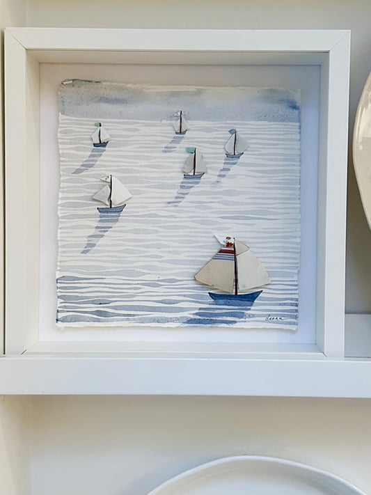 “Mixed media coastal artwork with watercolour waves and sailboats made from reclaimed china shards in a white frame.”